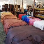 Leather hides displayed under large market tent.