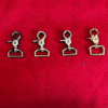 1trigger2 Four metal swivel hooks on red background.