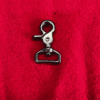 1trigger3 Metal swivel snap hook on red fabric.