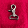 1trigger4 Metal clasp on red fabric background.