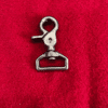 1trigger5 Metal swivel hook on red fabric background.