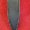 Black leather sheath on red background.