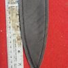 Knife sheath and ruler on red background.