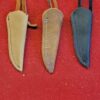 Three leather sheaths on a red surface.