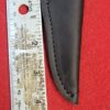 Black leather sheath next to measuring ruler.