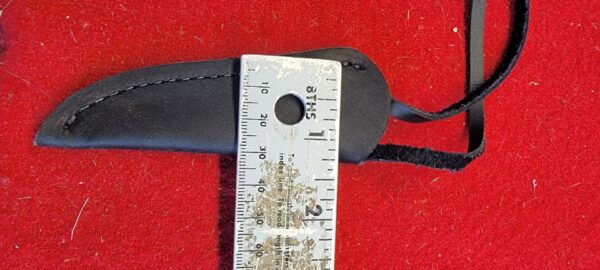 Black leather sheath with ruler on red.