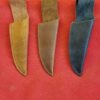 Three leather knife sheaths on red background.
