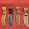 Four leather knife sheaths on red background.