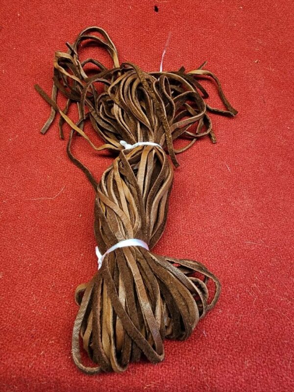 20240106_135601 Brown leather laces on red surface.