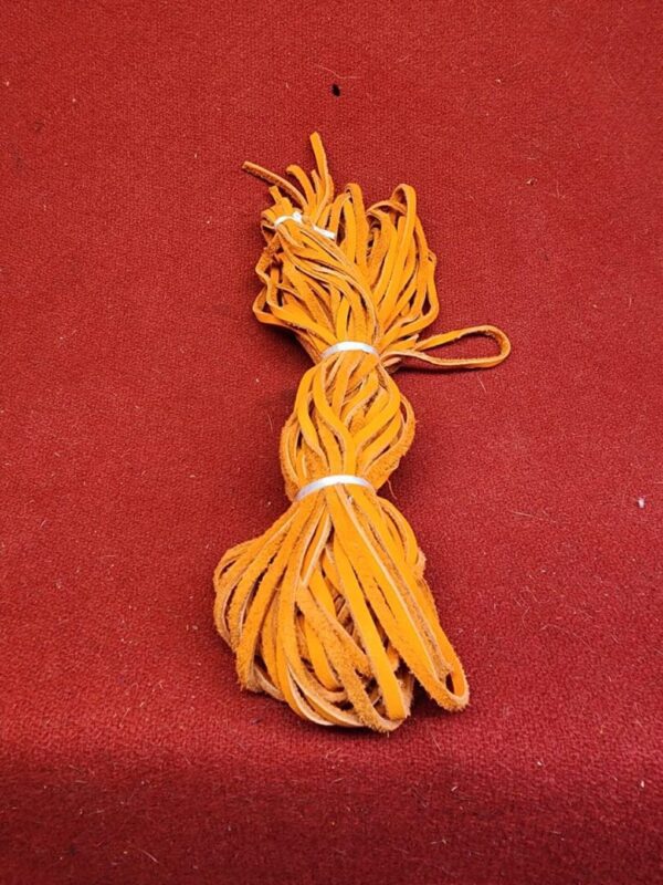 20240106_135647 Orange leather strips on red background.