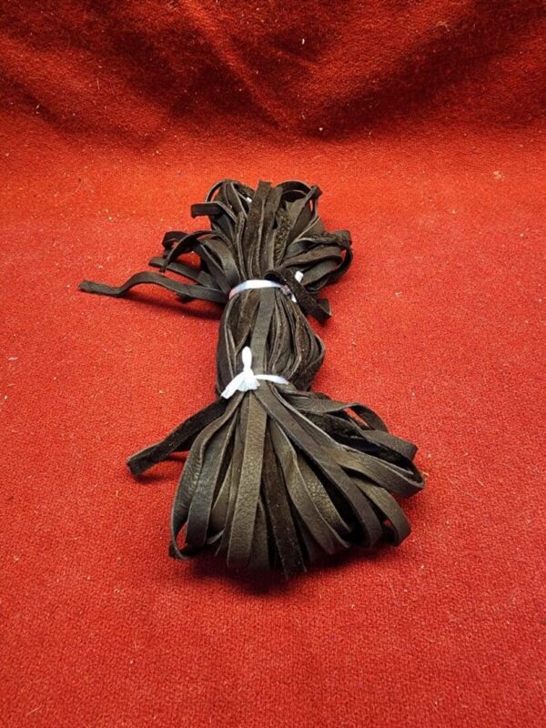 Bundle of black leather strips on red.