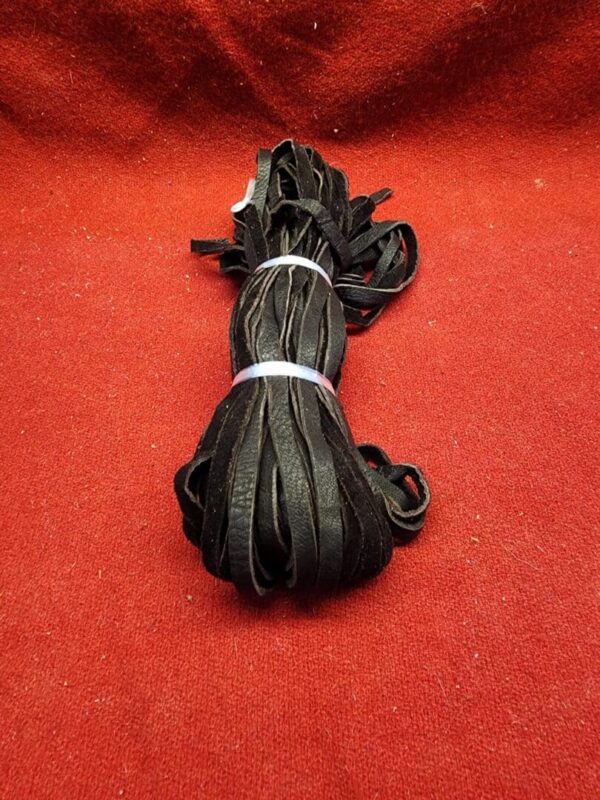 Bundle of black licorice strings on red.