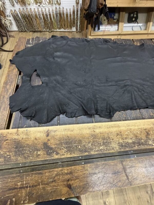 Black leather hide on wooden table.