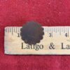 Brown scalloped disc on wooden ruler.