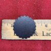 Black scalloped circle on wooden ruler.