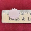 Pink scalloped circle on wooden ruler.