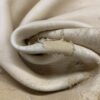 Close-up of torn, beige leather fabric.