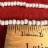 White beads with ruler on red fabric.