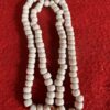 White beaded necklace on red fabric background.