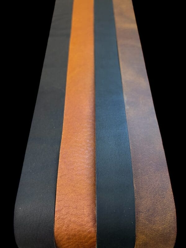 Four leather strips in black, brown, and orange.