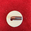 Bullet on round beige surface, red background.