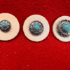 Three turquoise brooches on red background.