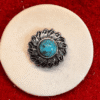 Turquoise and silver button on red background.