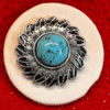 Silver brooch with turquoise stone on red.