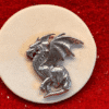 Silver dragon medallion on red background.
