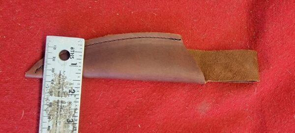 Leather knife sheath on red fabric background.