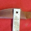 Leather knife sheath with ruler on red.