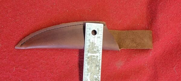 Leather knife sheath with ruler on red.