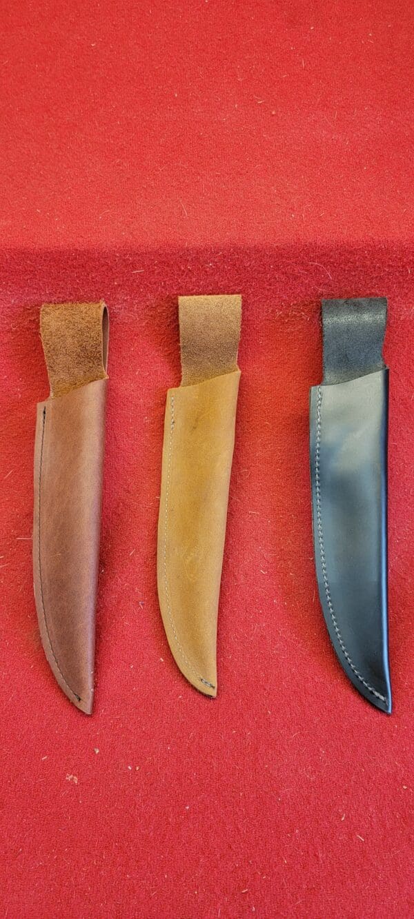 Three knife sheaths on a red surface
