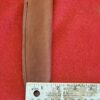 Leather sheath with ruler on red background.