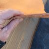 Hand holding piece of tan leather sheet.