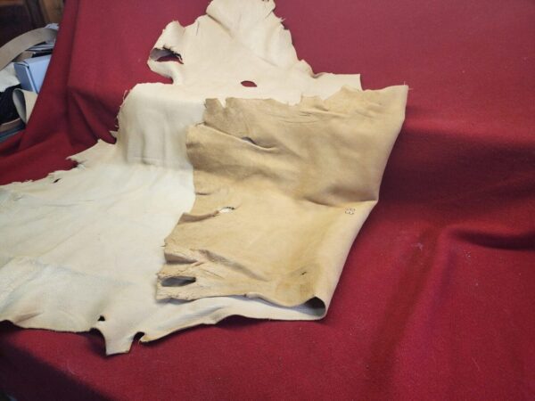 Tanned animal hides on red cloth background.