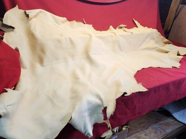 20231221_143835 Beige leather hide on red fabric background.