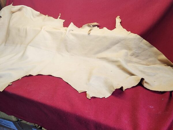 20231221_143839 Piece of beige leather on red fabric.