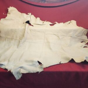 20231221_144306 Piece of beige leather on red cloth.