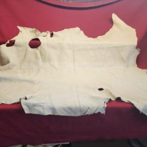 20231221_144422 Worn leather hide on red fabric background.