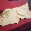 Beige leather hide on red fabric background.