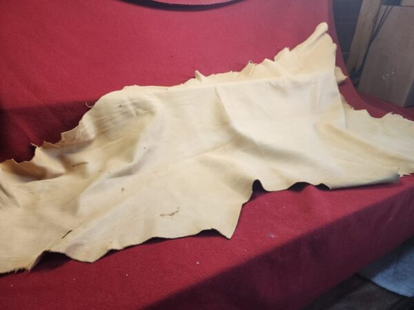 Beige leather hide on red fabric background.