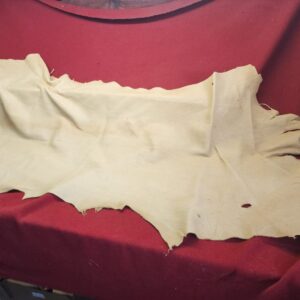 20231221_164500 Beige leather hide on red fabric display.