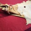 Torn leather hide on red fabric surface.