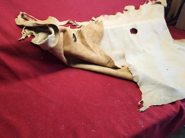 Torn leather hide on red fabric surface.
