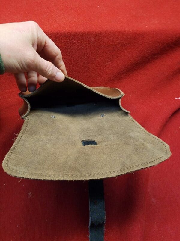 Open leather pouch on red fabric background.