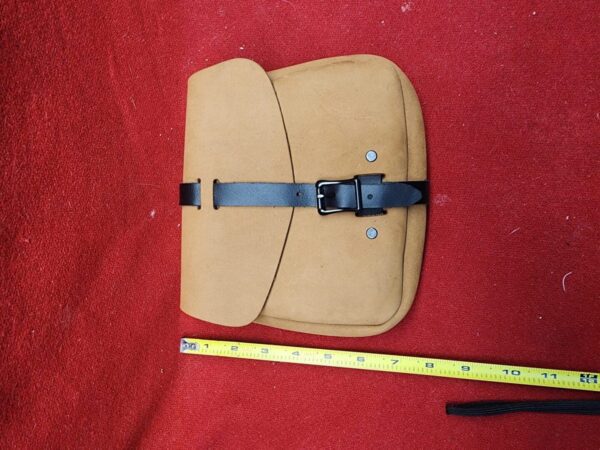 20231221_184219 Brown leather bag with measuring tape nearby.