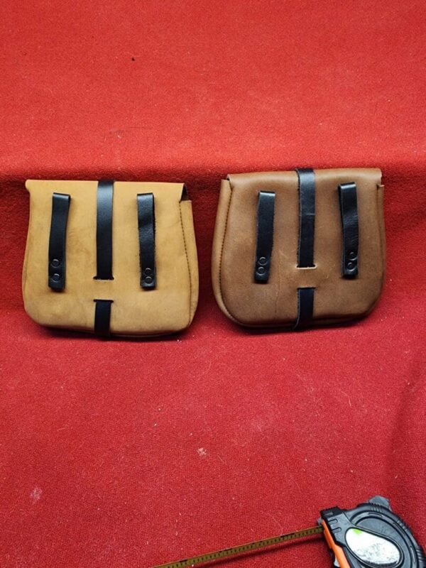 20231221_184241 Two leather pouches on a red surface.