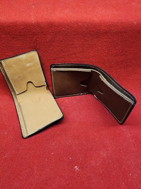 20231221_184408 Two open leather wallets on red surface.