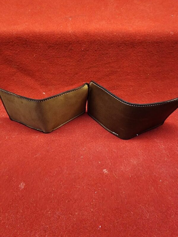 20231221_184416 Two brown wallets on red fabric background.